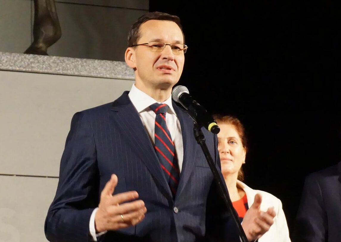 Premier Mateusz Morawiecki; w tle Iwona Mularczyk