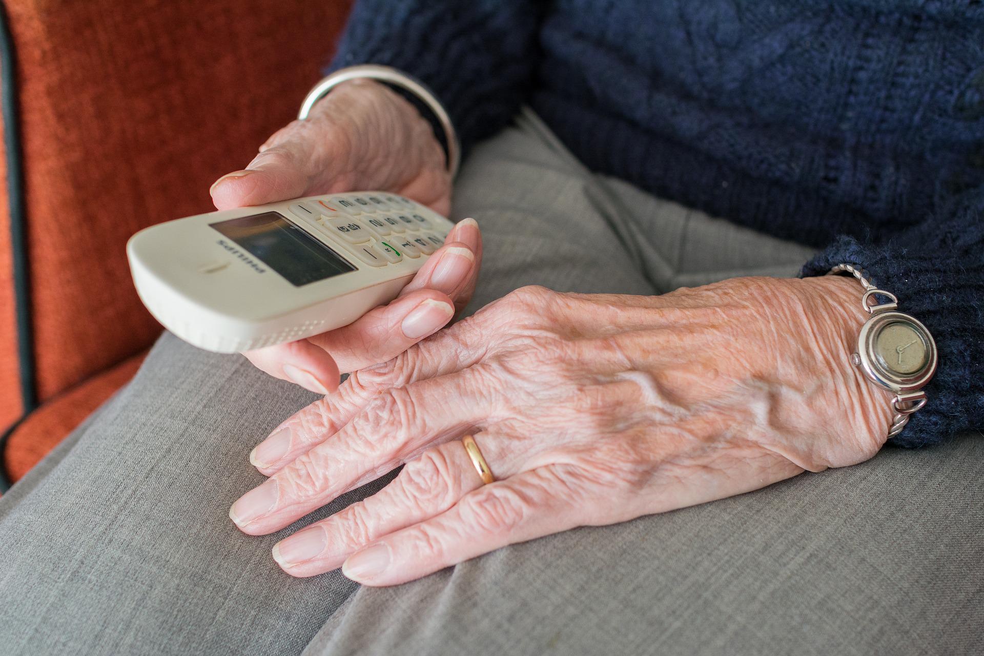 starsza kobieta trzyma w ręku telefon