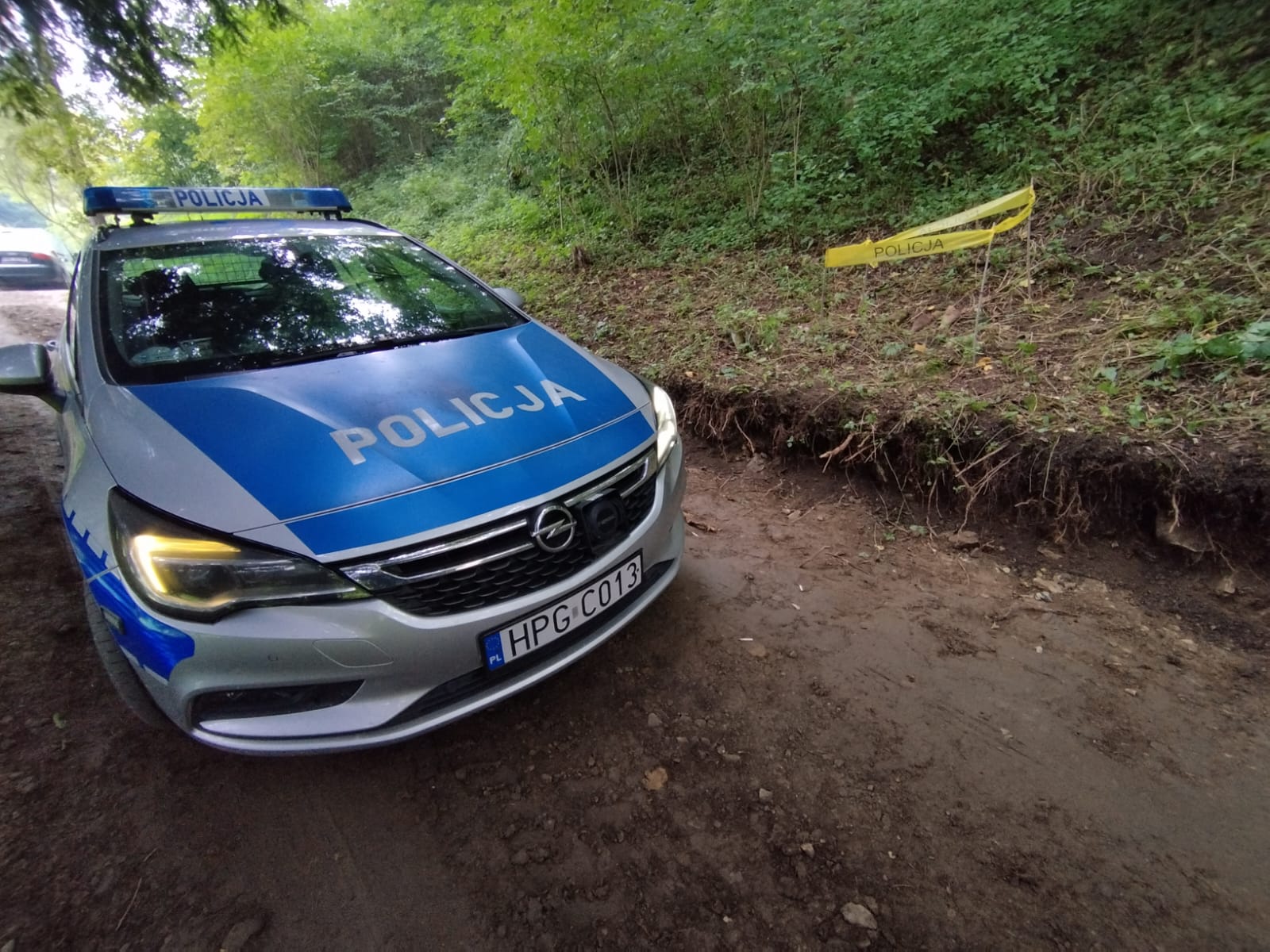 Oznakowany radiowóz obok oznaczone żółtą tasma z napisem policja ujawnione niewybuchy