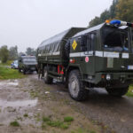 dwa pojazdy patrolu saperskiego, za nimi oznakowany radiowóz policji