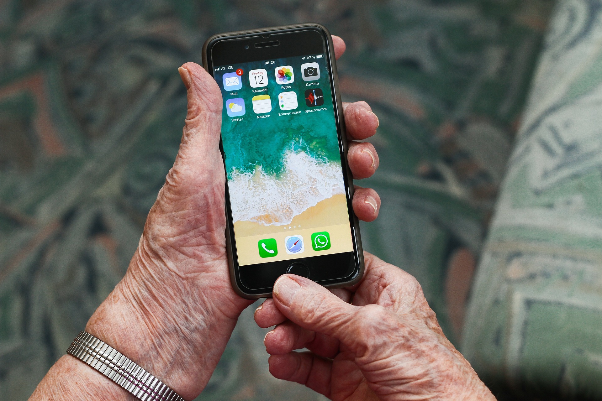 starsza osoba trzyma w ręku smartfon