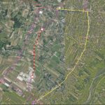 Satellite map of a town with color‑coded transit routes: a red dashed line between two white stop markers, a yellow loop around the area, and purple lines with intersections.