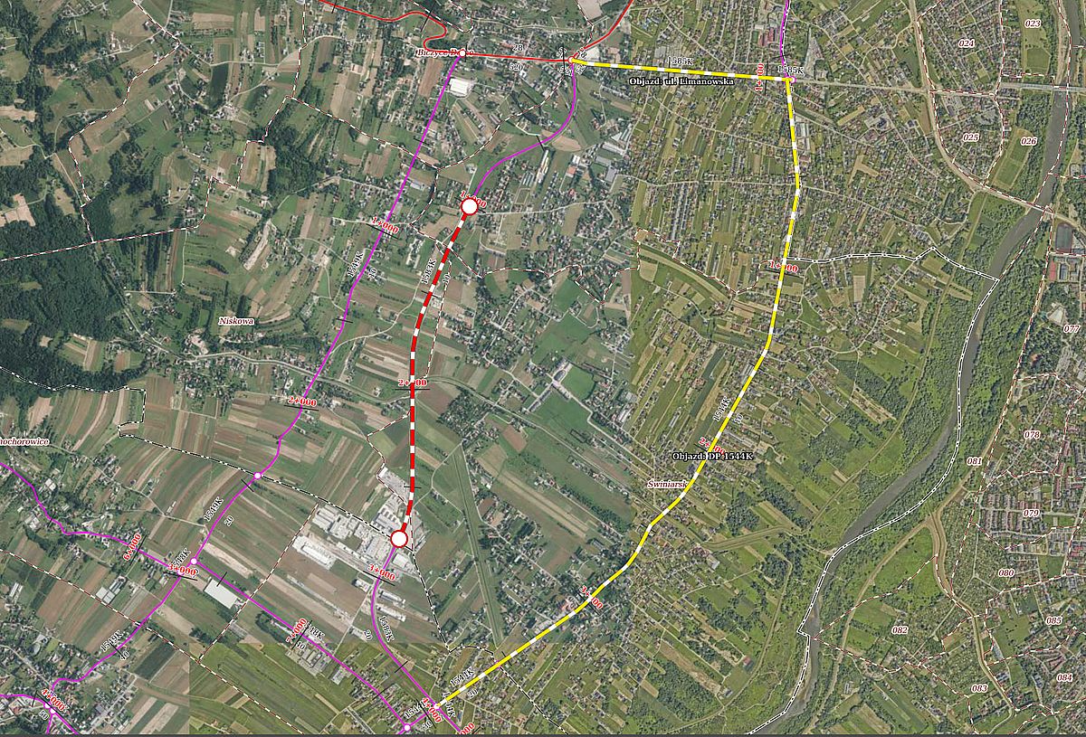 Satellite map of a town with color‑coded transit routes: a red dashed line between two white stop markers, a yellow loop around the area, and purple lines with intersections.