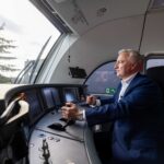 Train engineer in a blue suit operating the cockpit of a modern locomotive.
