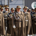 Group of soldiers in brown ceremonial uniforms standing in formation during a parade.
