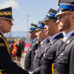 Senior officer in dress uniform shakes hands with a line of uniformed cadets during a formal outdoor ceremony.