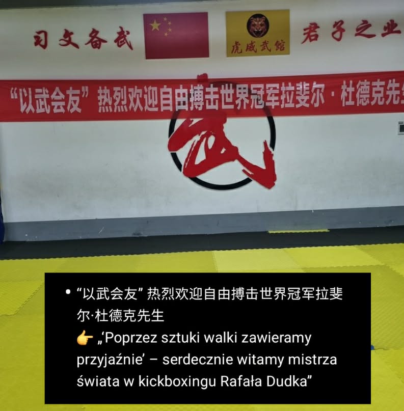 Dojo wall with a red Chinese banner welcoming world kickboxing champion Rafał Dudka; yellow mat in foreground.