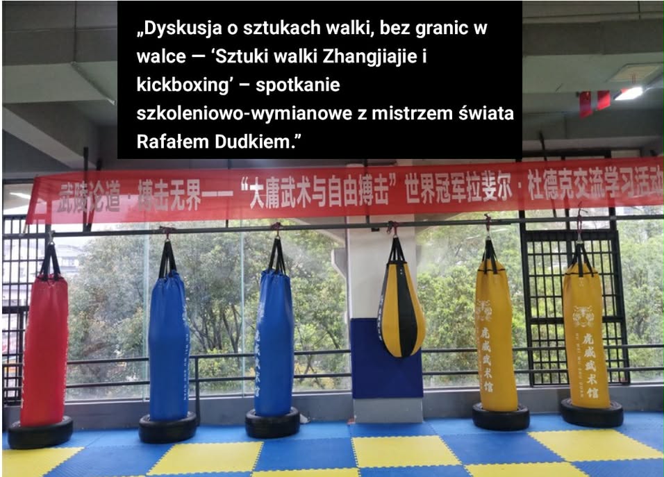 Indoor martial arts training space with red, blue, and yellow punching bags and a red banner with white Chinese characters hanging across the back wall. A text overlay in Polish describes a discussion about martial arts.
