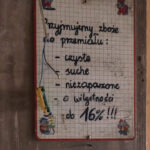 Small wall sign with handwritten Polish list about grain storage: clean, dry, pest-free, moisture under 16% (attached to a wooden surface with wires).