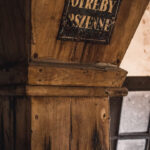 Old wooden post with a weathered metal plaque containing faded letters.
