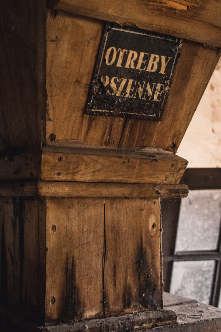 Old wooden post with a weathered metal plaque containing faded letters.