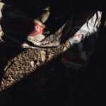 Dimly lit outdoor construction site with torn cement bags on rocky ground.