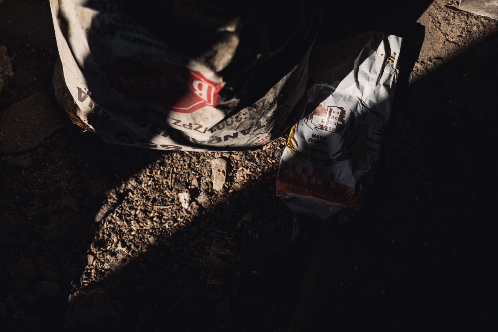 Dimly lit outdoor construction site with torn cement bags on rocky ground.