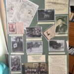 Display board filled with vintage photos, handwritten documents, and captions in Polish on a green background; a historical collage.