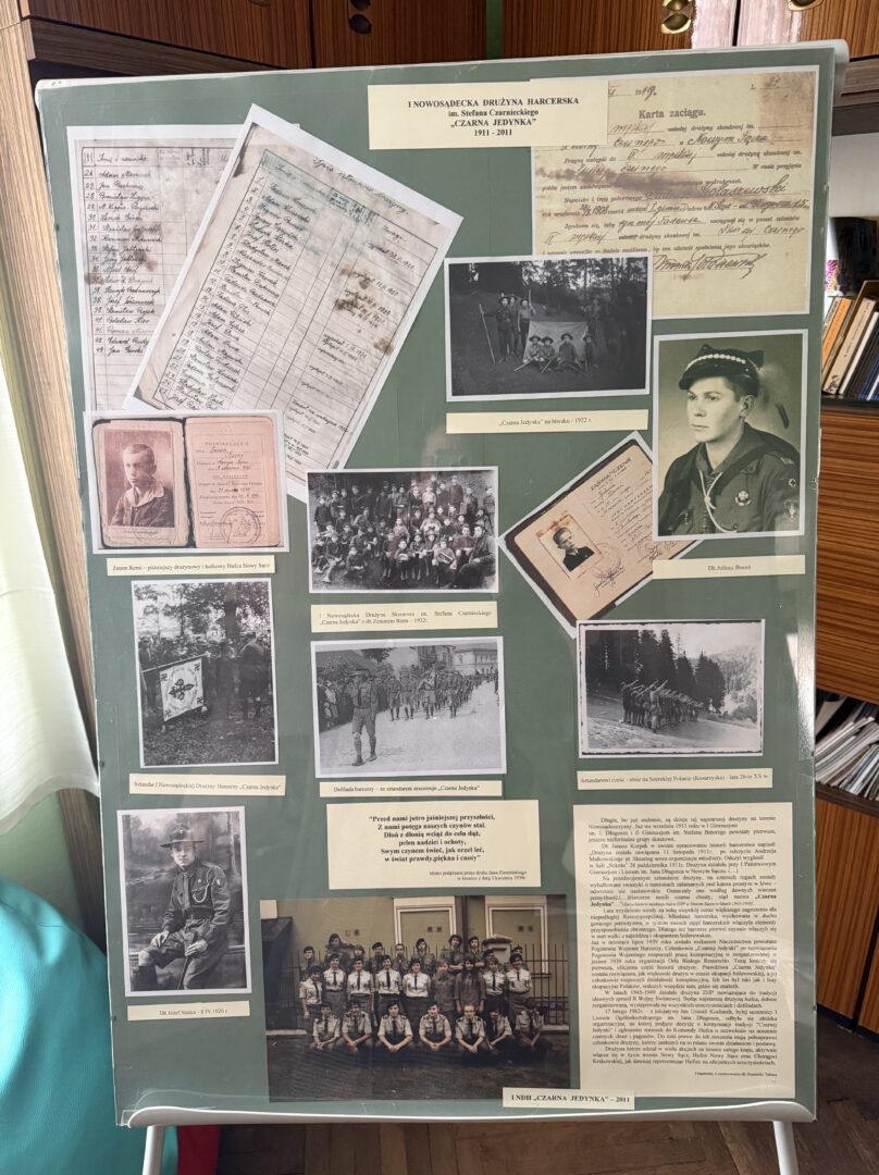 Display board filled with vintage photos, handwritten documents, and captions in Polish on a green background; a historical collage.