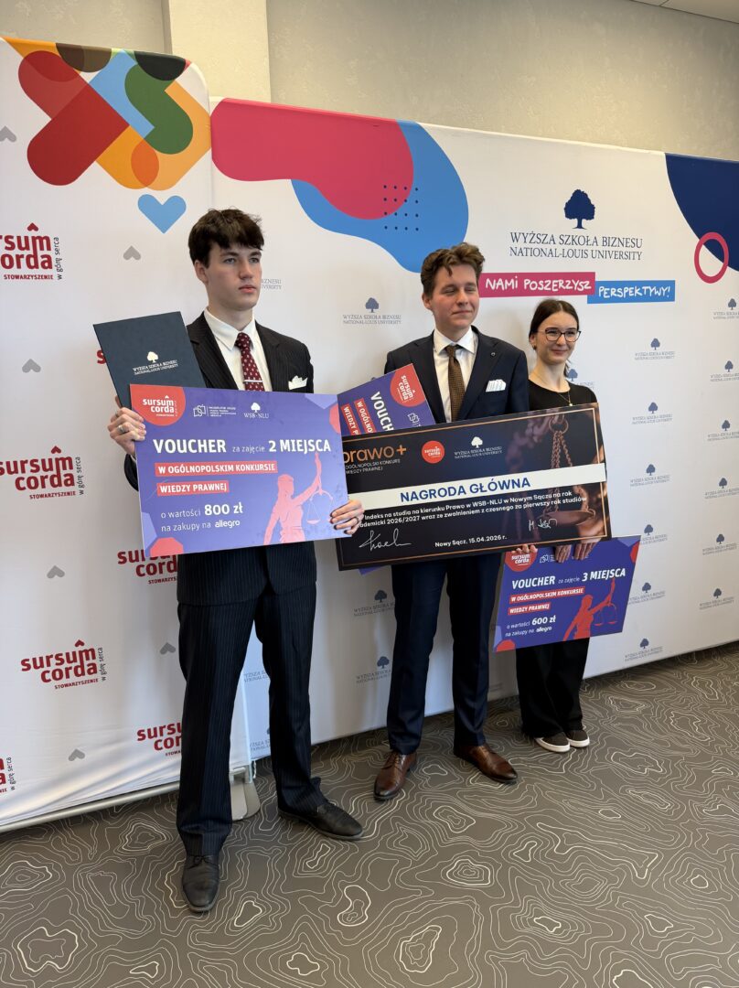 Three people in suits pose with oversized prize vouchers during an award ceremony.