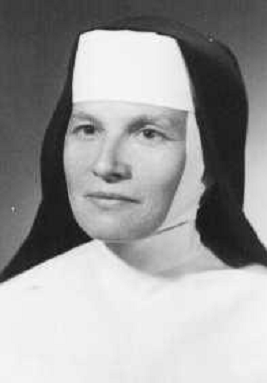 Portrait of a Catholic nun in a white wimple and black veil, looking at the camera.