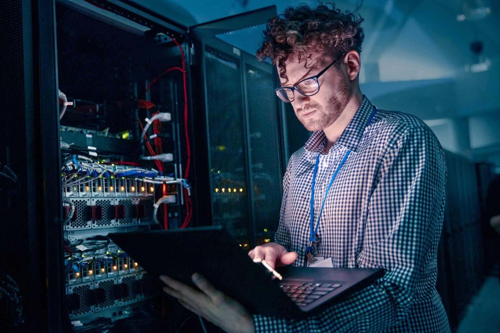 IT technician inspecting server rack with a laptop in a data center