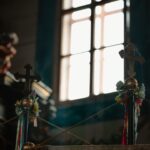 Interior of a church altar with cross finials and colorful ribbons, lit by a bright window behind.