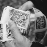 Close-up of hands flipping through a black-and-white photo album.