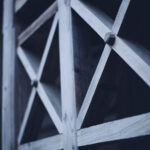 Close-up of a weathered wooden lattice with diagonal cross braces.
