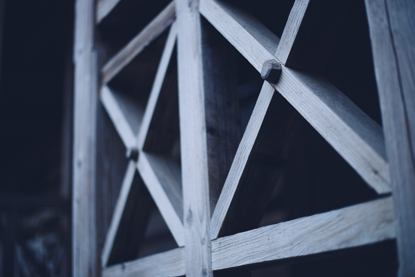 Close-up of a weathered wooden lattice with diagonal cross braces.